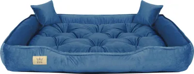 A blue velvet dog bed with two small pillows on a white background.