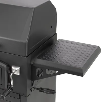 A close-up view of a black charcoal grill, focusing on the side shelf and part of the lid.