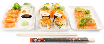 A top-down view of a sushi platter with various types of sushi and sashimi, accompanied by chopsticks and a wrapper.