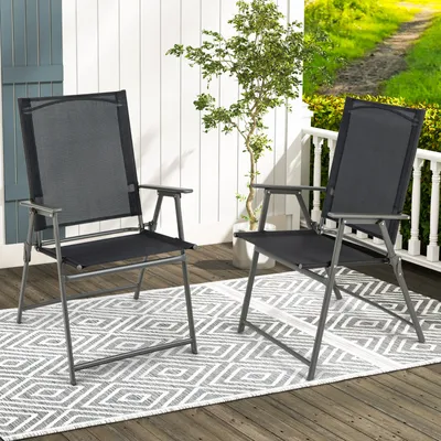 Two black folding garden chairs are placed on a wooden deck with a patterned rug underneath.