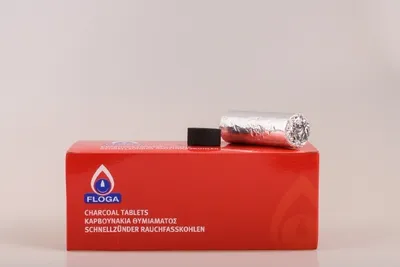 A red box of charcoal tablets with one tablet and a wrapped roll of charcoal tablets on top.