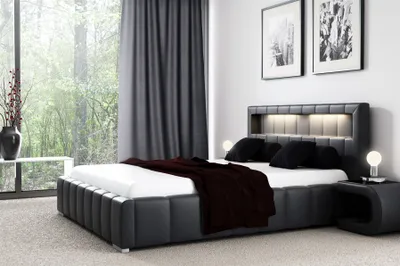 A modern bedroom with a large bed, nightstand, and window view.