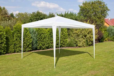 A white gazebo is set up on a green lawn in a backyard, surrounded by trees and bushes. A house with a red roof is visible in the background.