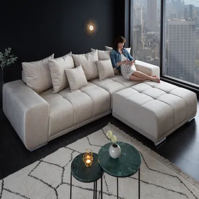 A woman sits on a large sectional sofa in a modern living room with a city view.