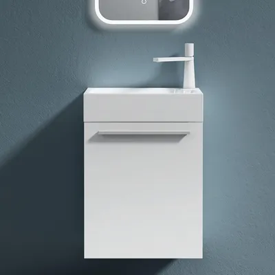 A white bathroom vanity set with a sink and faucet is mounted on a textured blue wall.