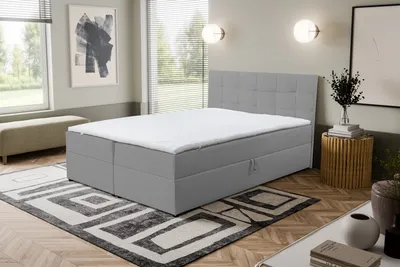 A bedroom scene with a bed, rug, and artwork.