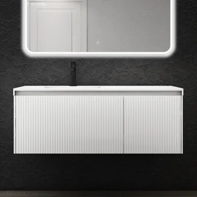A modern white vanity unit with a black faucet is mounted on a dark textured wall, with a backlit mirror above.