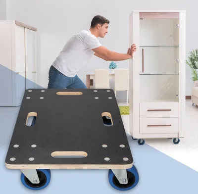 A man is pushing a tall cabinet with a furniture dolly in the foreground.