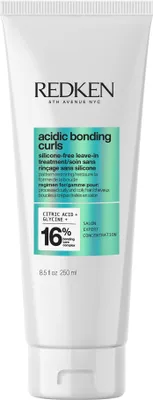 A white tube of Redken hair product with green and blue accents.