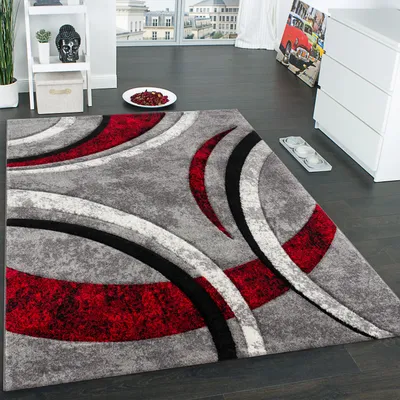 A modern living room with a rug, a shelf with decor, and a dresser with artwork.