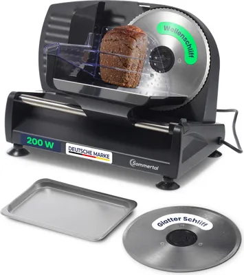 A black electric slicer with a loaf of bread on it, a metal tray, and a spare blade.