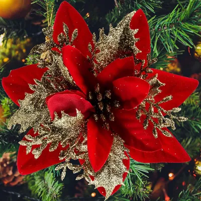 A close-up of a red and gold artificial poinsettia flower ornament on a Christmas tree.