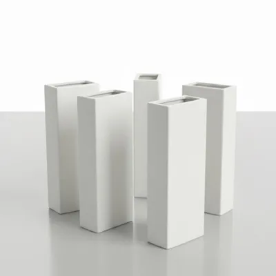 A set of five white ceramic vases arranged on a light gray surface against a white background.