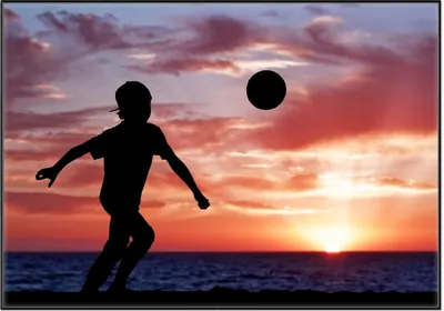 Produktbild von Wallario Wandbild Fußball - Kleiner Junge spielt im Abendrot, Größe: 70,30 x 100,30 cm, Poster mit schwarzem Aluminiumrahmen