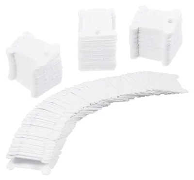 A collection of white plastic bobbins for storing embroidery thread, arranged in stacks and a curved line.
