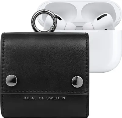 A black leather case for AirPods with a silver carabiner is shown in the foreground, with an open white AirPods charging case containing two white AirPods in the background.