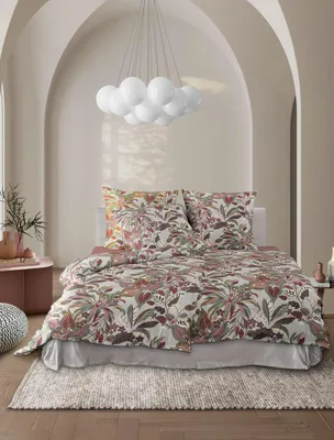 A bedroom scene with a bed dressed in floral patterned bedding, under a modern chandelier.