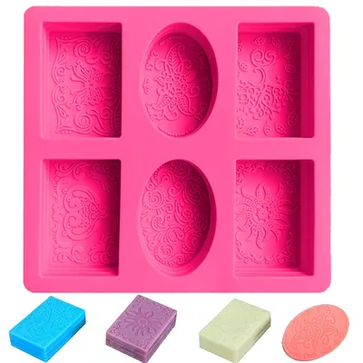 A bright pink silicone mold for making soaps or candles, with intricate patterns in each cavity. Below the mold are four small, colorful examples of finished soaps.
