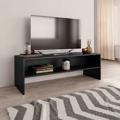 A black TV stand with a television and decorative items on it, placed on a wooden floor with a rug in front.