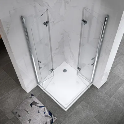 A corner shower cabin with glass doors and a white base, set against marble-tiled walls and gray tiled flooring. A small rug with a geometric pattern is placed on the floor in front of the shower.