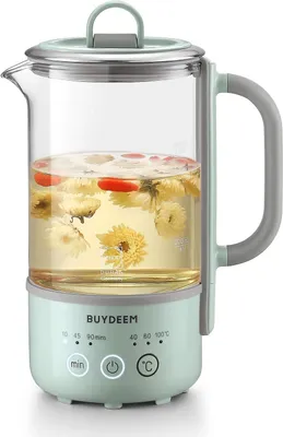 A close-up shot of a green electric kettle filled with water, tea leaves, and goji berries.