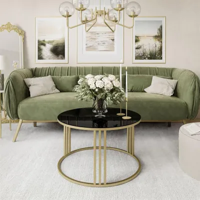 A living room scene with a green sofa, a round coffee table, and artwork on the wall.
