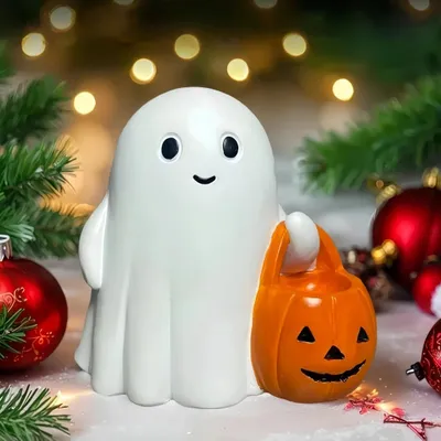 A cute ghost figurine holding a pumpkin candy bucket, surrounded by festive decorations like pine branches and red ornaments.