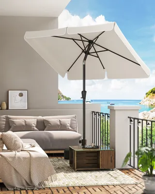 A balcony with a sofa, coffee table, and umbrella overlooking the ocean.