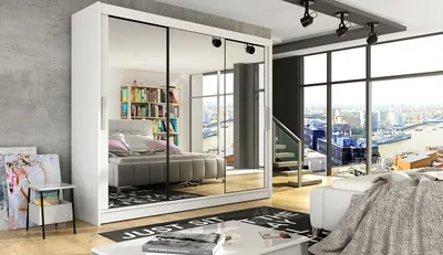 A spacious bedroom with a large mirrored wardrobe, a bed, and a view of a city skyline through a large window.