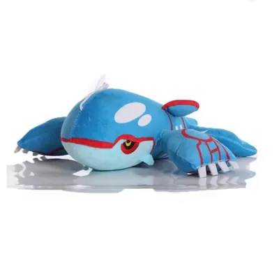 A plush toy of the Pokemon Kyogre lying on a reflective surface against a white background.