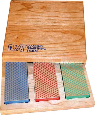 A wooden box containing three diamond sharpening stones of different colors.
