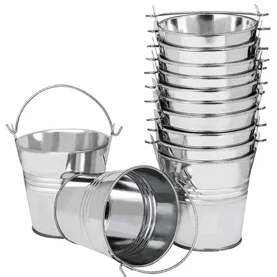 A collection of small, silver metal buckets with handles, some stacked and one lying on its side.