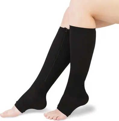 A close-up shot of a person's legs wearing black compression knee-high socks with a zipper.