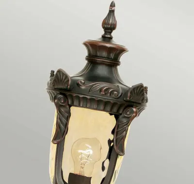 A close-up view of an outdoor lantern with decorative metalwork and a glass shade.