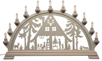 Ein traditioneller Schwibbogen aus dem Erzgebirge zeigt ein Waldhaus mit Tieren und Bäumen im Scherenschnittstil beleuchtet von mehreren kleinen Kerzen die eine gemütliche Atmosphäre schaffen