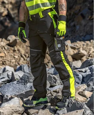 A person wearing work pants and gloves stands on a rocky surface.
