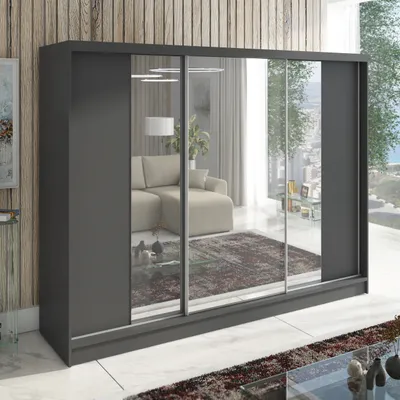 A large, modern wardrobe with mirrored sliding doors, reflecting a living room interior.