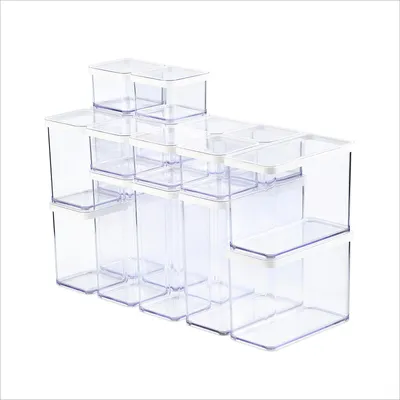 A set of clear plastic food storage containers with white lids, arranged in a stepped formation.