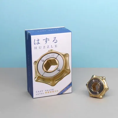 Verpackung und Rätselspiel „Cast Valve“ mit goldenem Metallpuzzle vor hellblauem Hintergrund.