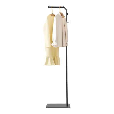 A black freestanding coat rack with a slate base, displaying a yellow dress and a cream jacket on hangers.