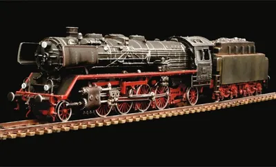 A detailed model of a steam locomotive on a model railway track against a black background.