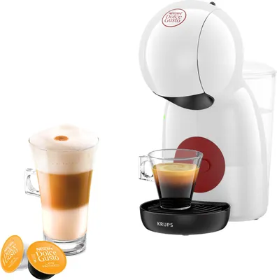 A white Krups Dolce Gusto coffee machine with a cup of coffee and two coffee capsules.