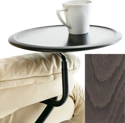 A close-up view of a tray table attached to a beige leather armchair, with a white mug on the tray. A swatch of grey wood grain is in the lower right corner.