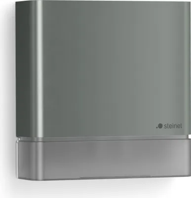 A product shot of a gray and silver STEINEL IS 180 Laser-Sensor mounted on a white wall.