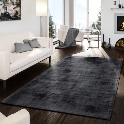 A modern living room with a white sofa, a fireplace, and a large dark gray rug.