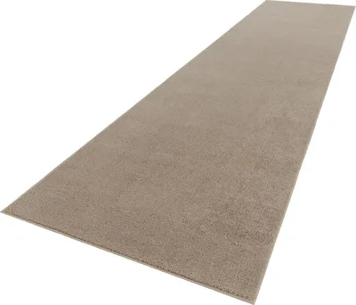 A long, narrow beige rug is shown from a slightly elevated angle against a white background.