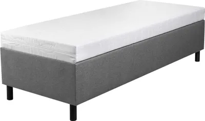 A single bed with a gray upholstered base and a white mattress on top, shown from a slightly elevated side angle against a white background.