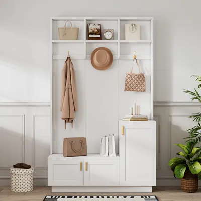 A white entryway organizer with a bench, shelves, and hooks, decorated with bags, a coat, and a hat.