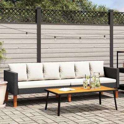 An outdoor patio scene with a black rattan sofa and a wooden coffee table.