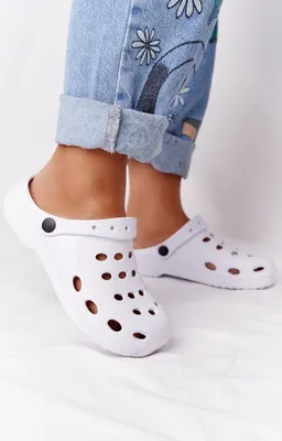 A close-up shot of a person's feet wearing white clogs.